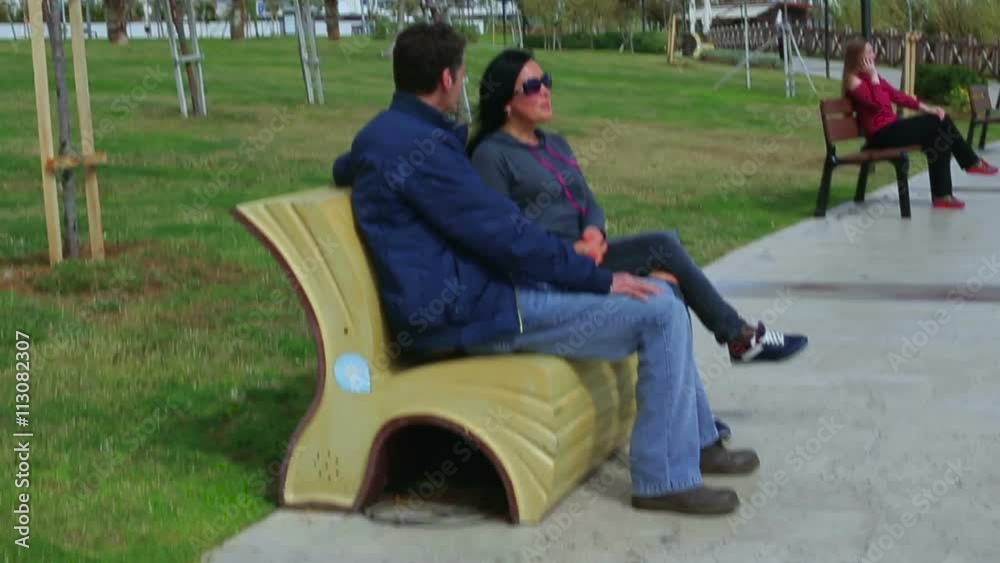 Lovers man and woman talking while sitting on a park bench Lovers man and woman talking while sitting on a park bench