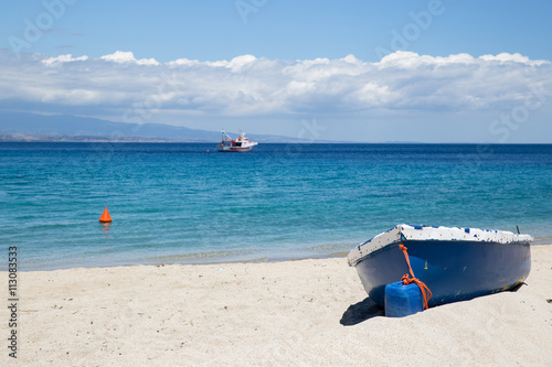 Fototapeta Naklejka Na Ścianę i Meble -  A yaucht in the turquoise sea waters and a blue boat on the white sand