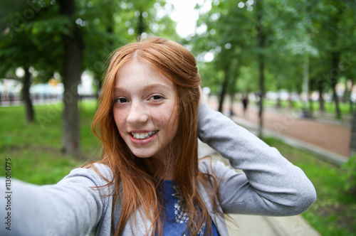 Girl walks in the park and makes selfie, happy.