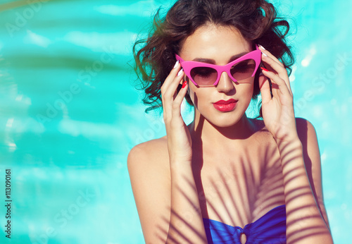 Summer beach style portrait a beautiful young woman wearing bikini and sunglasses under a palm tree