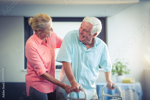 Canvas Print Senior woman helping senior man to walk with walker