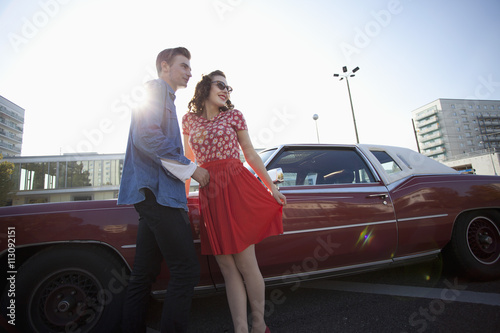 A cheerful rockabilly couple standing next to a vintage car  photo