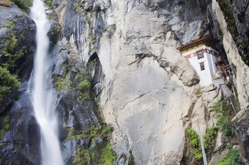 A waterfall flowing past a temple built into the side of a cliff, Tigers Nest (Taktsang Goemba), Paro Valley, Bhutan