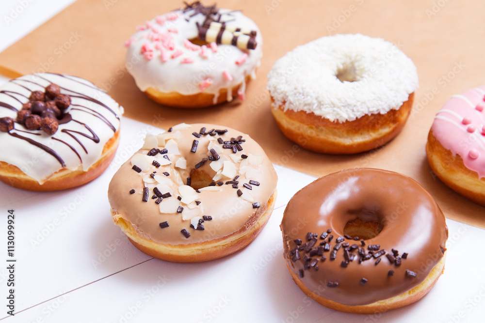 Colored delicious donuts with sprinkles on a white wooden background Colored delicious donuts with sprinkles on a white wooden background