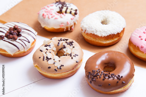 Colored delicious donuts with sprinkles on a white wooden background