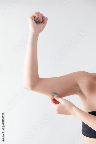 二の腕を摘む女性・白バック photo
