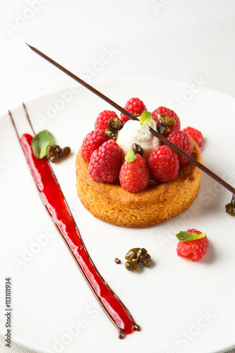 Sable breton or  shortbread with vanilla cream and raspberry coulis on white dish photo
