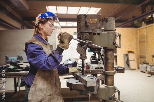 Female welder using a drill press photo