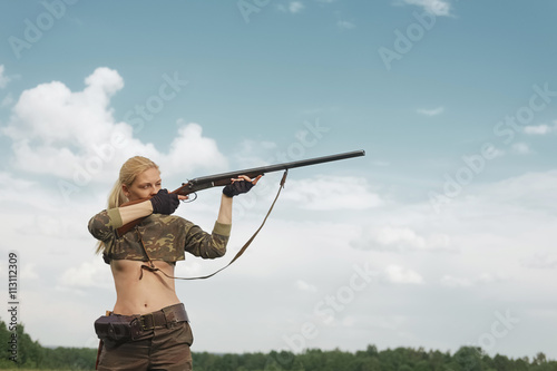 Attractive hunter girl with hunting double-barreled rifle shooti