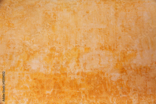 Stained, textured, yellow colored concrete wall, ideal for backgrounds and textures.