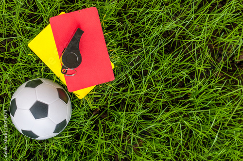 Soccer referee outfit a yellow and red card with ball on lawn of stadium. Football background