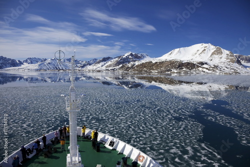 Tourists on board Arctic polar exploration cruise ship near Monaco glacier in summer, Liefdefjorden, Spitzbergen, Svalbard photo