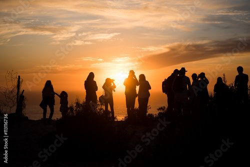 Silhouettes of people watching sunset