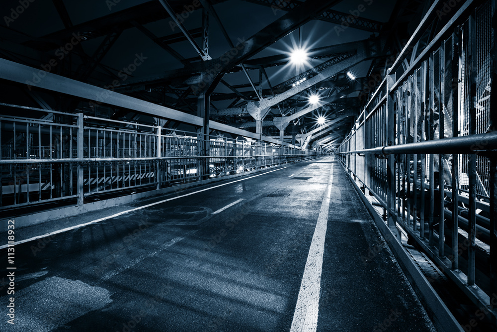 Moody monochrome view of Williamsburg bridge pedestrian walkway by night in New York City