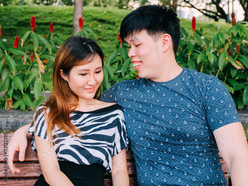 Asian couple sitting on the bench in the park together © twinsterphoto