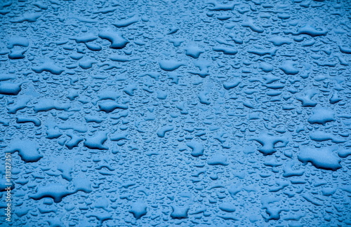 Raindrops retained on blue metallic paintwork of a car.Wet blue car texture background.