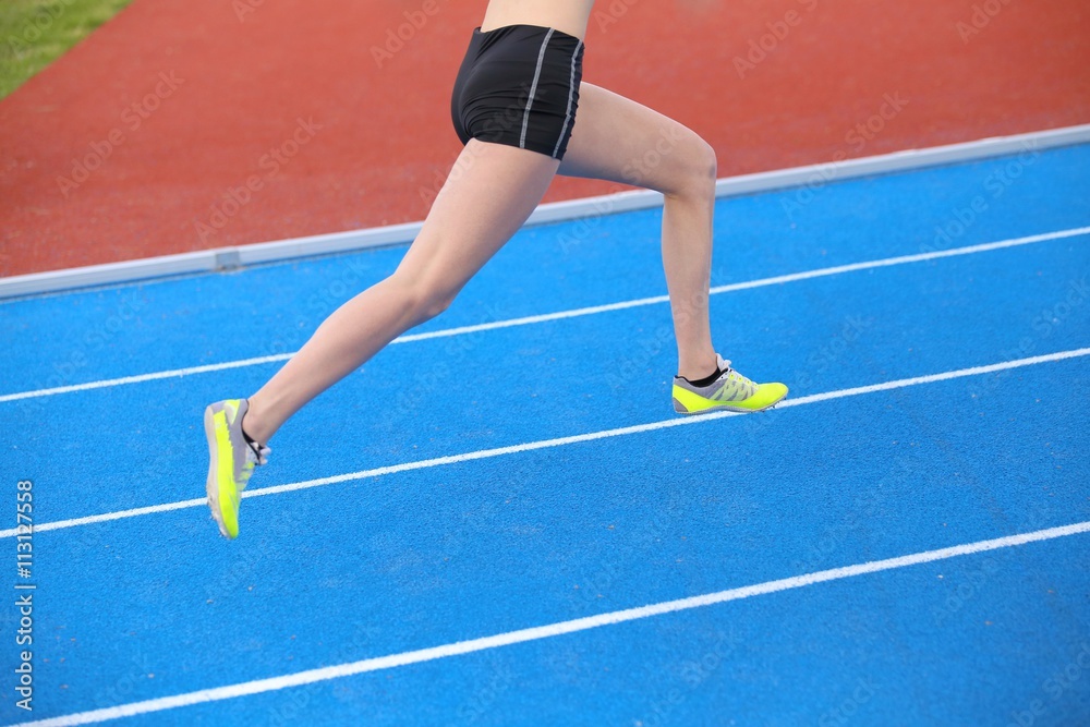 long legs of young female runner running on athletic track with