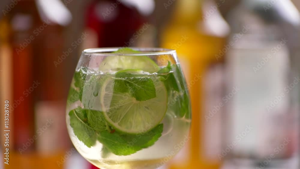 Tongs put lime into drink. Beverage with lime and ice. Hugo cocktail served at bar. Mineral water and elderflower syrup. Tongs put lime into drink. Beverage with lime and ice. Hugo cocktail served at bar. Mineral water and elderflower syrup.