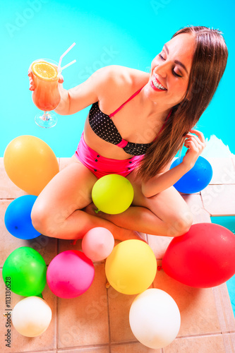 Happy woman with balloons and cocktail.