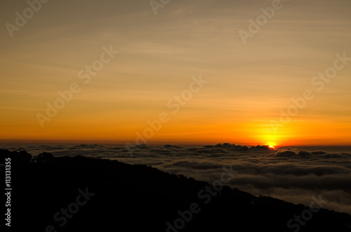 Sunrise over foggy valley mountains