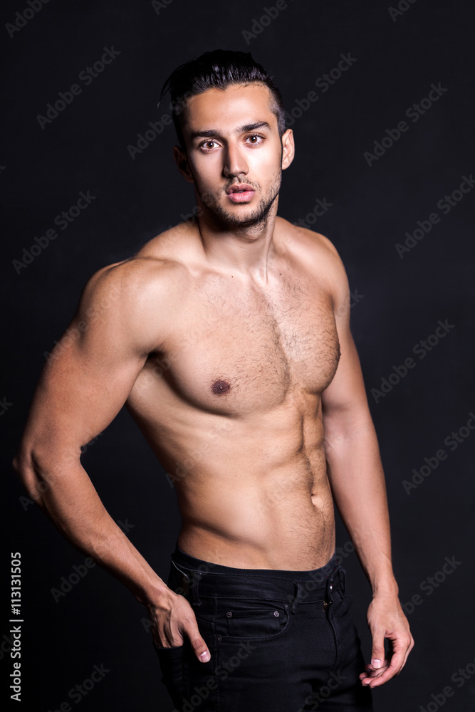 Sexy shirtless male model flirting against black background