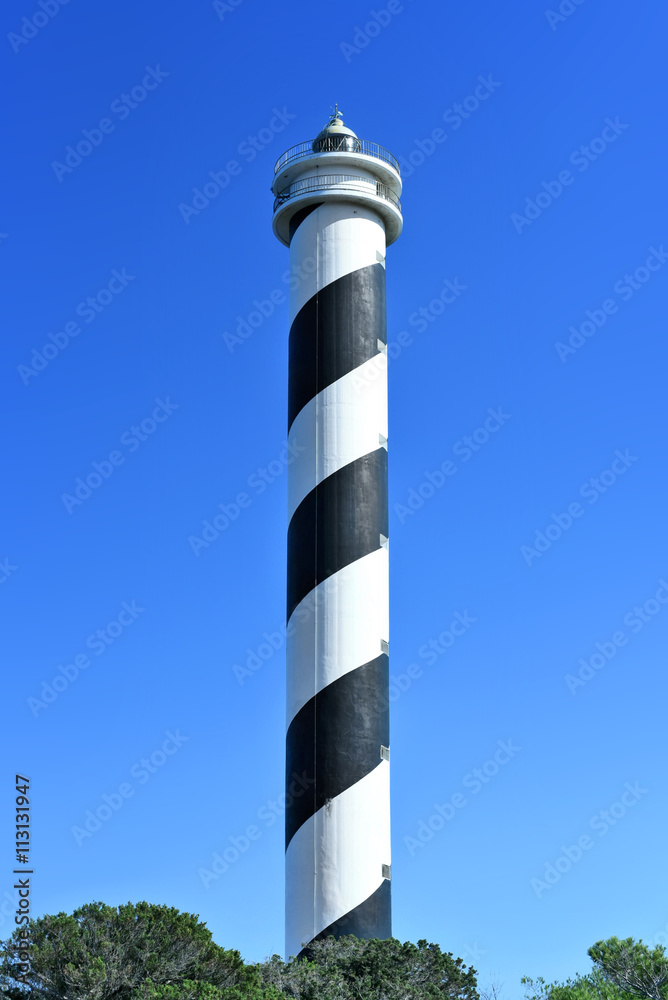 Obraz premium Black and white striped lighthouse on a cliffcoast. Beacon and copy space. 