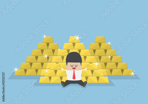Businessman sitting with a pile of gold bars