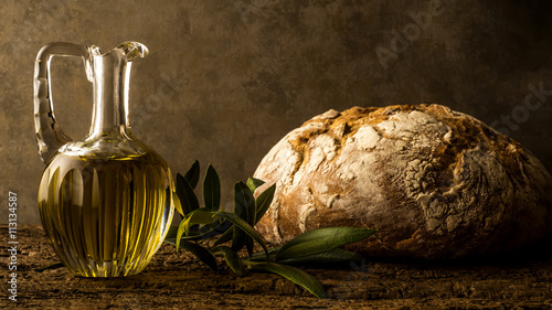 Virgin olive oil in vintage oil jar and rustic bread