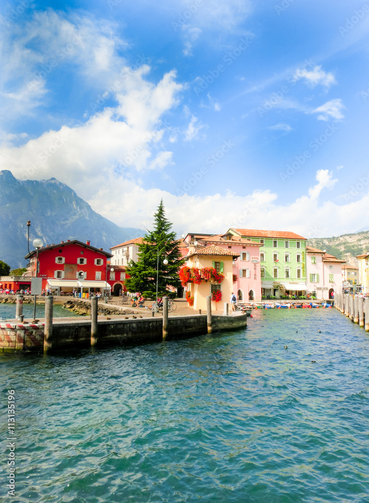 Torbole, Italy - September 21, 2014: Lake Garda boardwalk with houses, tourists and boats