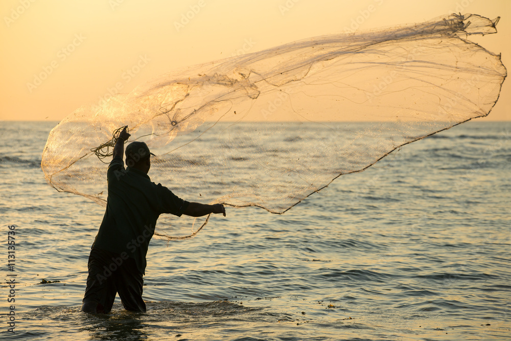 Silhouette of the unidentified Indian fisherman throwing net in sea on sunset in Fort Kochi, India. - obrazy, fototapety, plakaty 