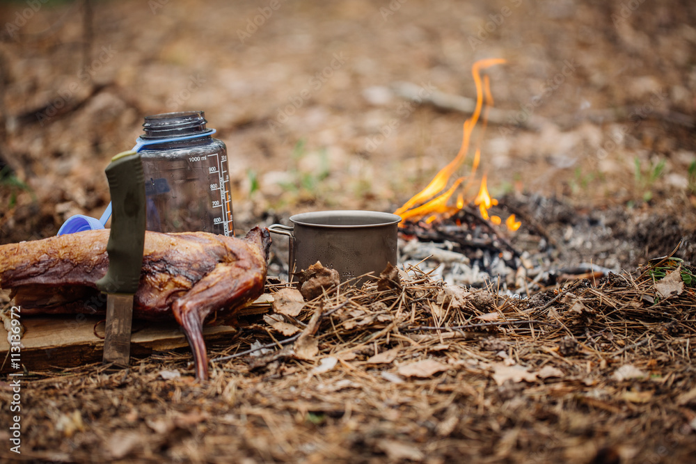 grilled rabbit meat on wooden board, with knife, water bottle an grilled rabbit meat on wooden board, with knife, water bottle an