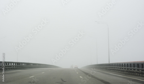 highway across the bridge in fog with cars in the distance