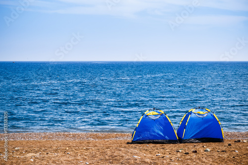 Two tents on beach by Mediterranean sea.