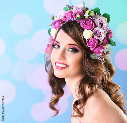 Beautiful young woman wearing floral headband on a blue festive background