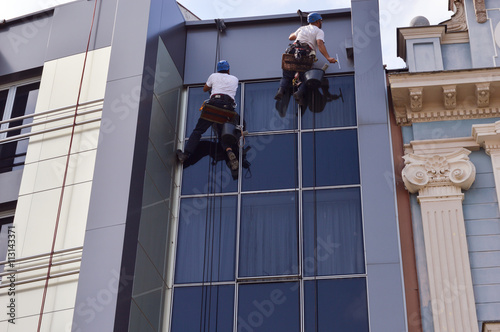 Two Workers cleaning windows service on high rise building