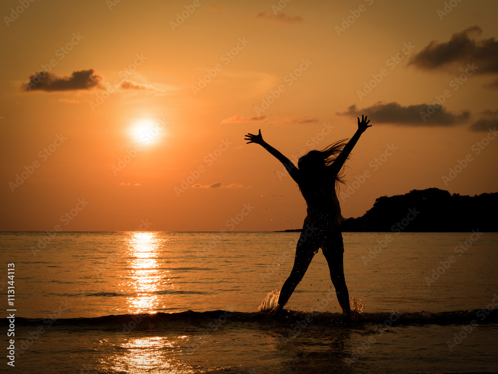 silhouette of happy young woman jumping in sea at sunset beach in summer. Freedom life concept. Holiday. vacation.
