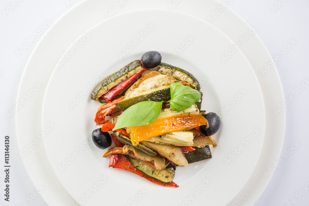 Roasted vegetables on a white plate on wwhite background. Top vi