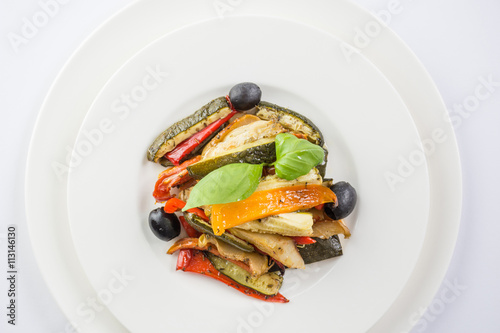 Roasted vegetables on a white plate on wwhite background. Top vi photo