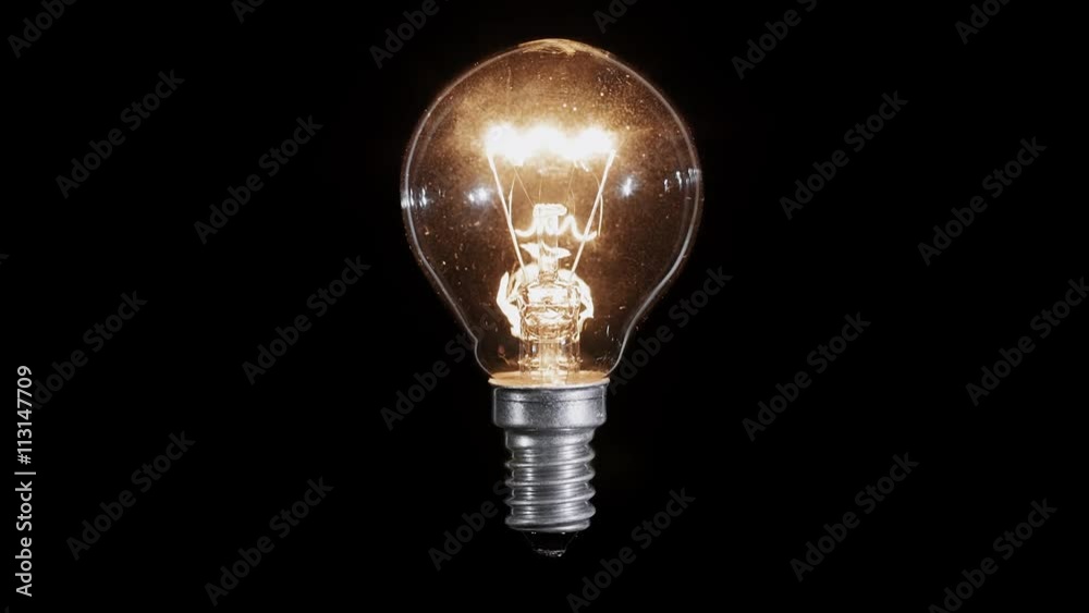 Lamp light bulb twinkles over black background, macro view, loop ready