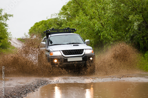 Mitsubishi Pajero Sport moving by water making lots of splashes photo