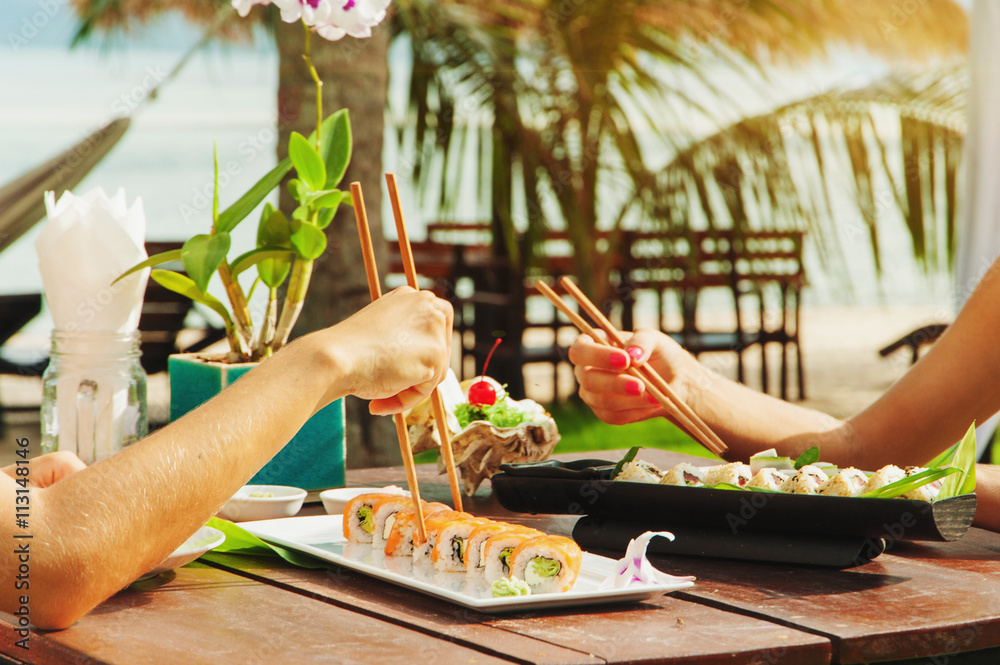 Two girls have a dinner with japanese sushi roll at the beach Two girls have a dinner with japanese sushi roll at the beach