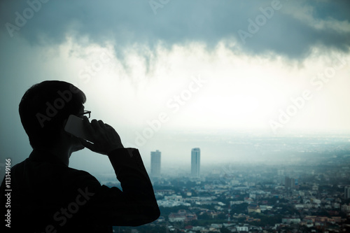 Man talking mobile phone with stormmy sky over big city background