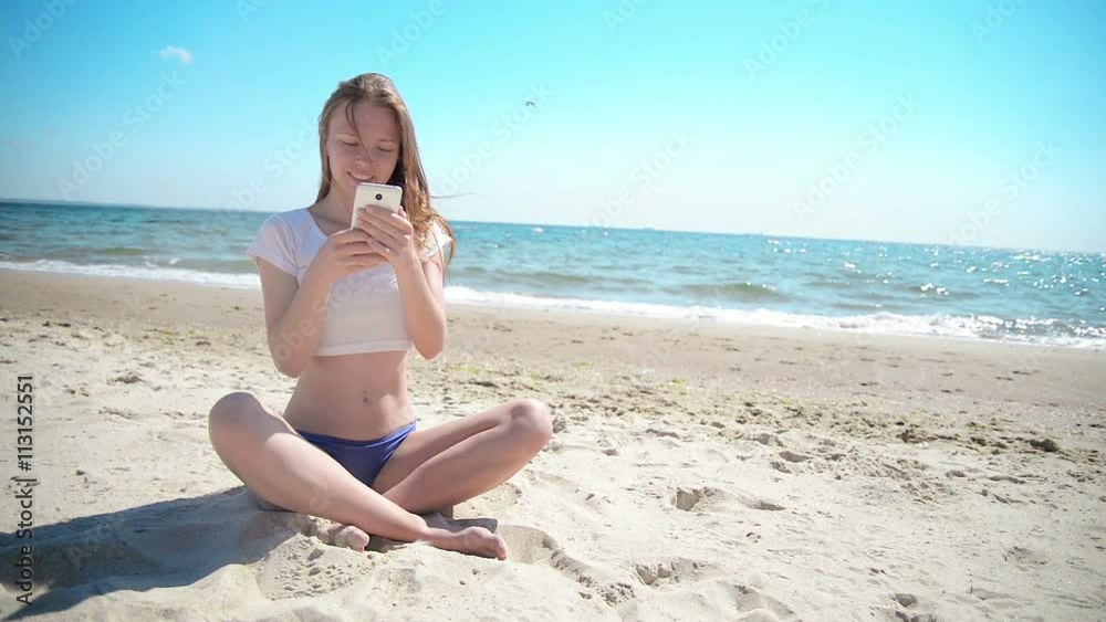 Girl with mobile phone sitting on sand near sea and blue sky. First love. Girl with mobile phone sitting on sand near sea and blue sky. First love.