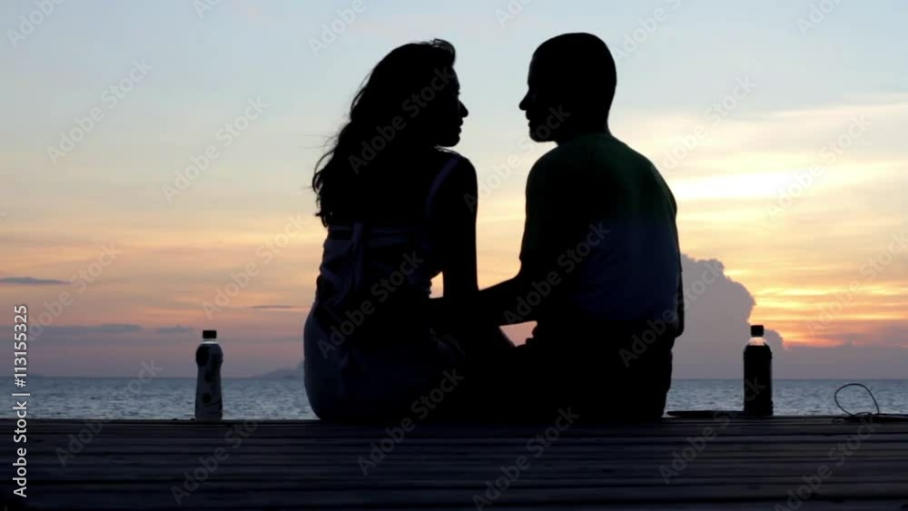 Young couple sitting on the pier at sunset background
Young couple sitting on the pier at sunset background