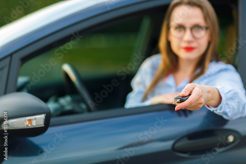 Young pretty woman sitting in a car with the keys in hand