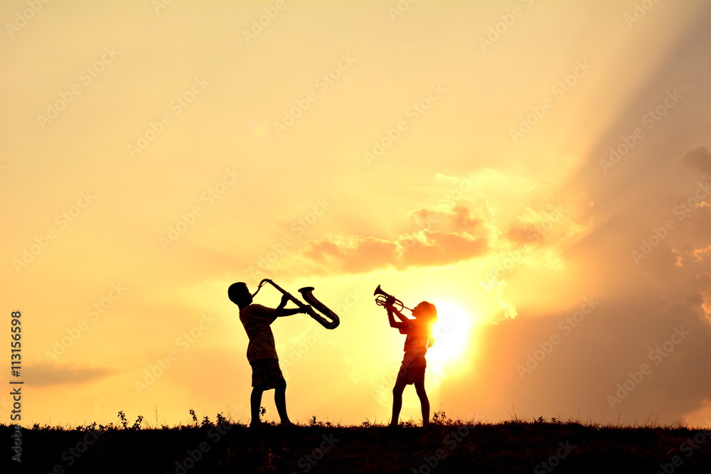 Silhouette children playing musical at sky sunset .warm tone