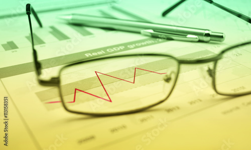 Glasses and pen on financial chart and graph, success concept, g