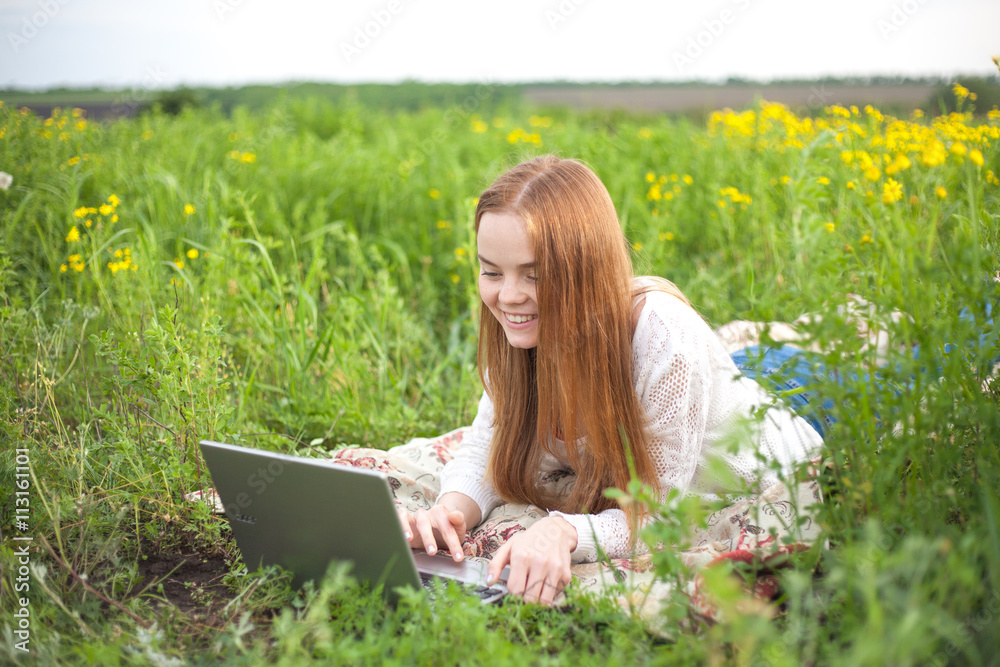 Young smiling woman with notebook in park looking at notebook computer Young smiling woman with notebook in park looking at notebook computer