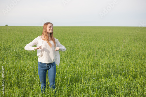 woman with open arms in the green wheat field at the morning