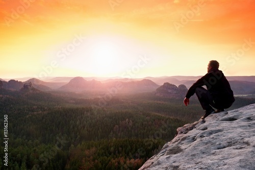 Man enjoing watching orange daybreak in mountains